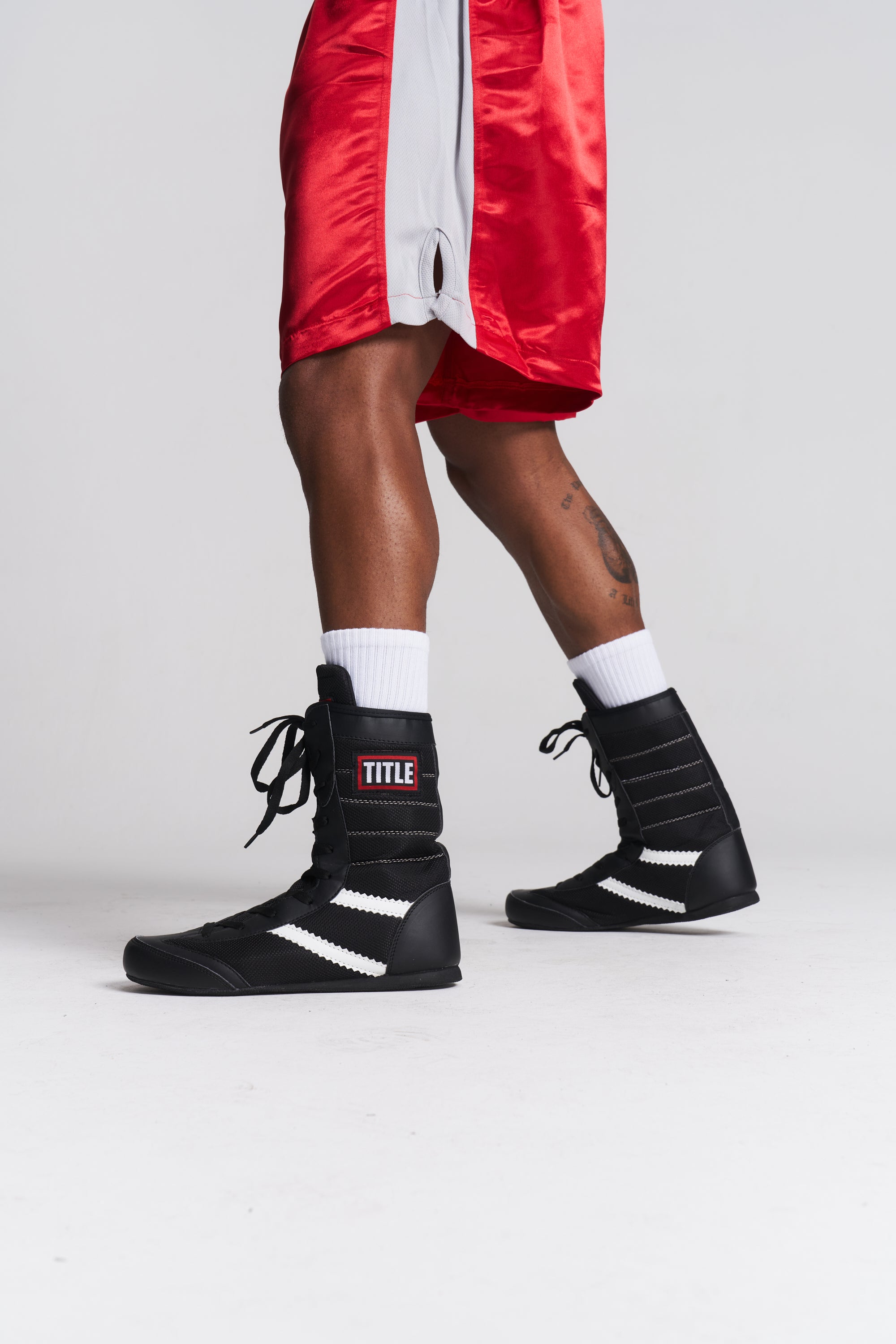 TITLE Boxing South Africa black high-top boxing boots with white stripes worn by a boxer in red shorts
