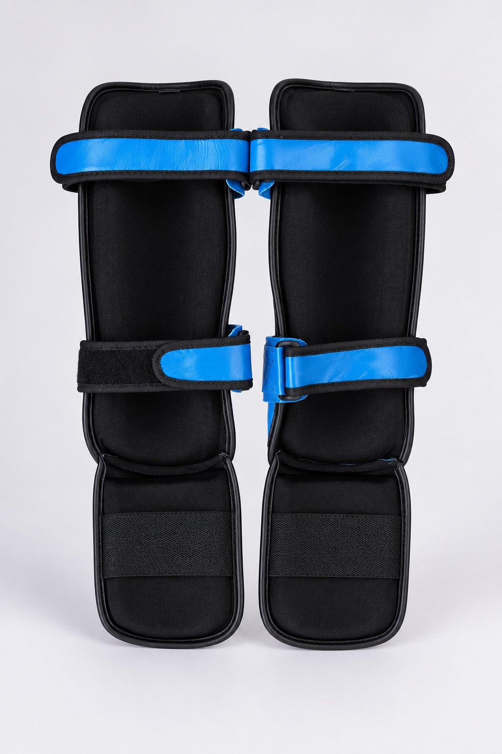 Back of TITLE blue shin guards: black lining, two blue leather calf straps and an elastic under-foot band