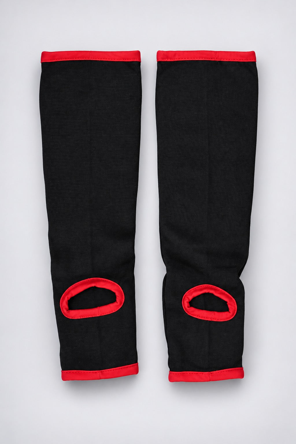 Back of TITLE black elasticated shin and instep guards with red-bound heel openings and no straps