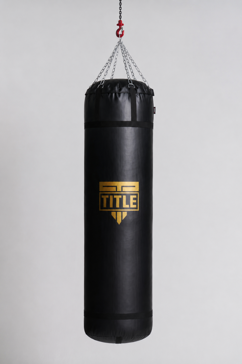 A black heavy punching bag with a gold and black TITLE logo, suspended by chains from a red hook against a light gray background.