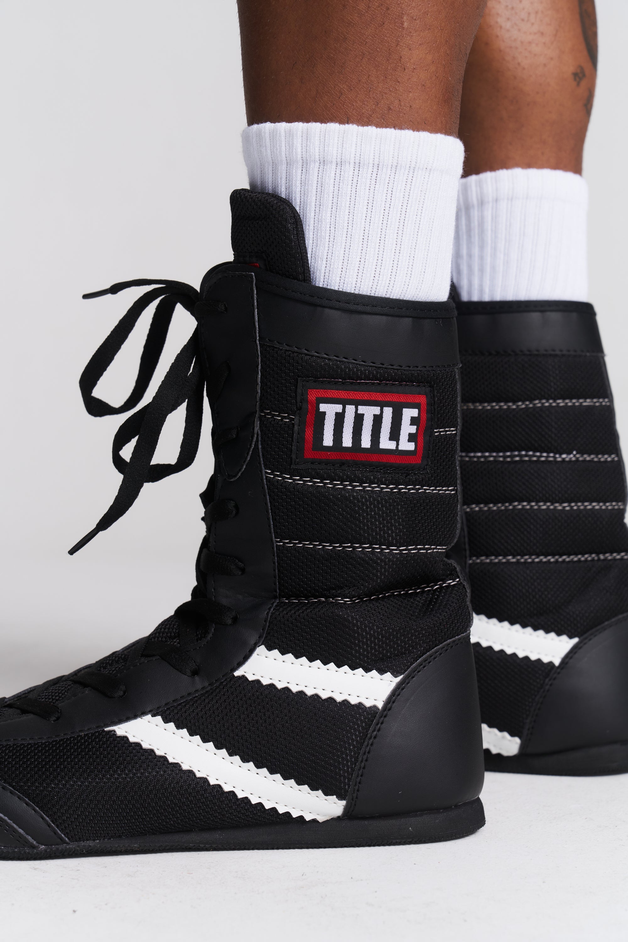 TITLE Boxing South Africa black high-top boxing boots with white accents and ankle support worn with white socks
