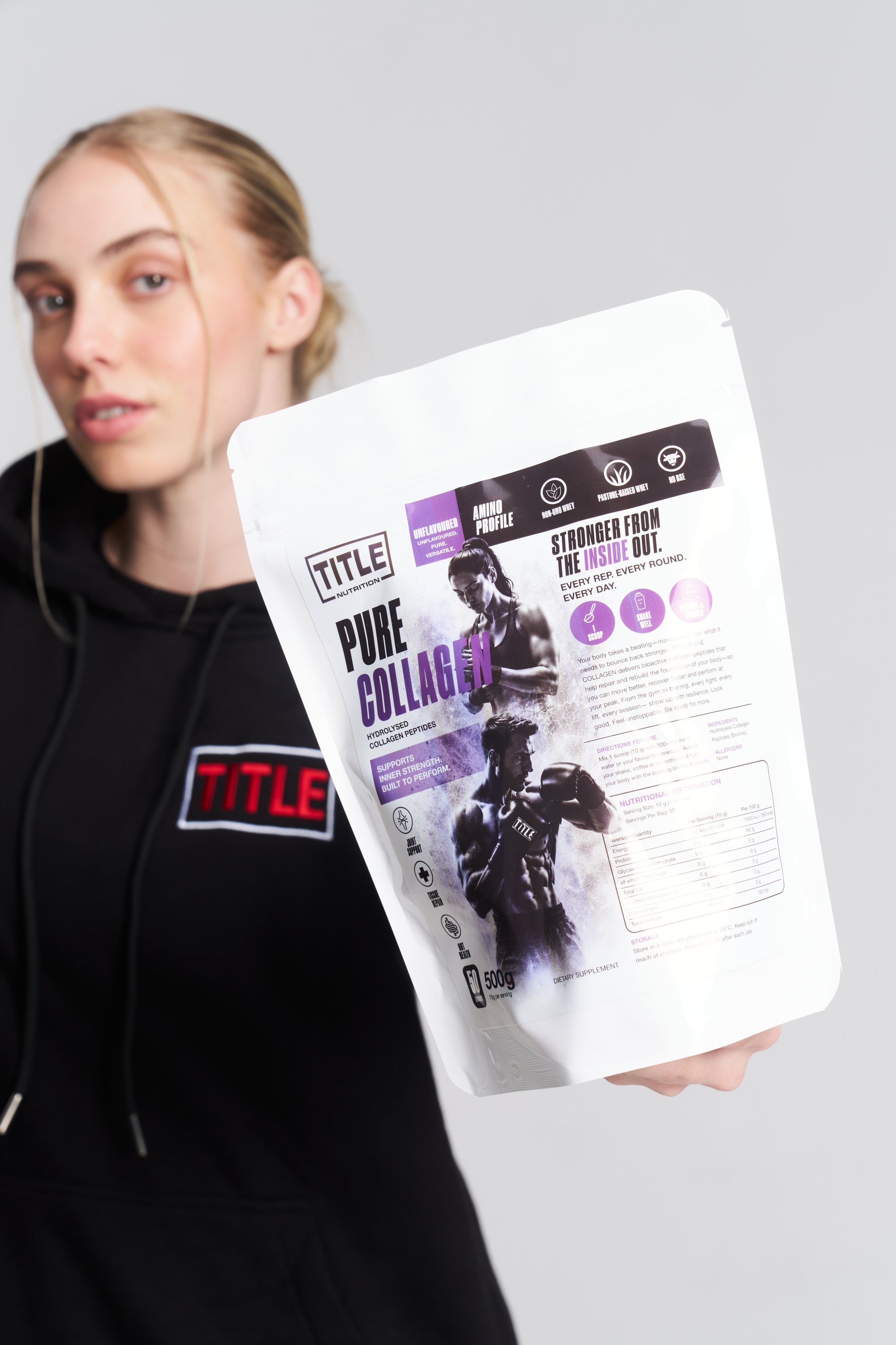 A woman in a black hoodie holding a 500g bag of TITLE Boxing South Africa Pure Collagen hydrolysed bovine peptides.