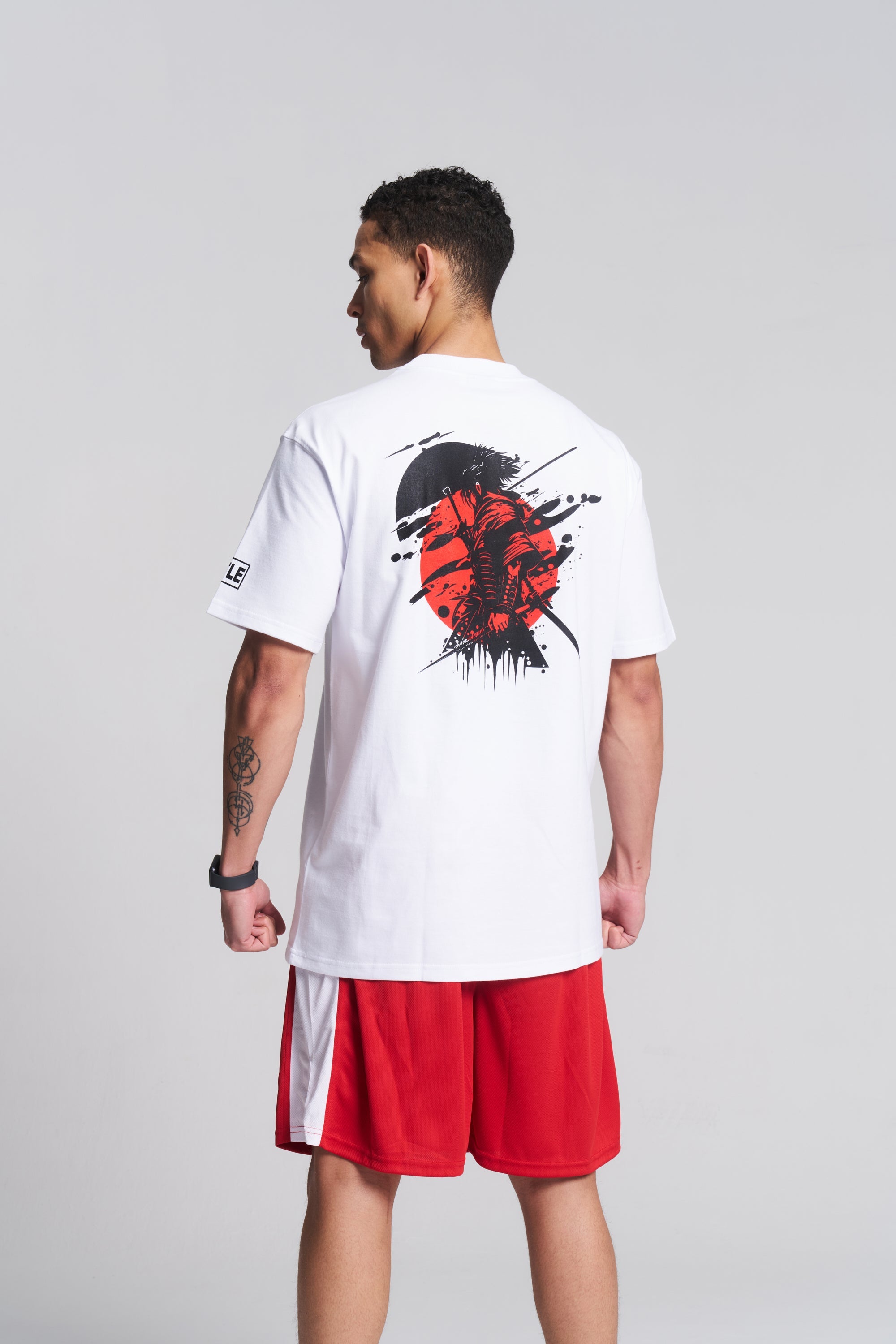 A man wearing a white TITLE Boxing South Africa oversized cotton t-shirt with a black and red samurai back print.