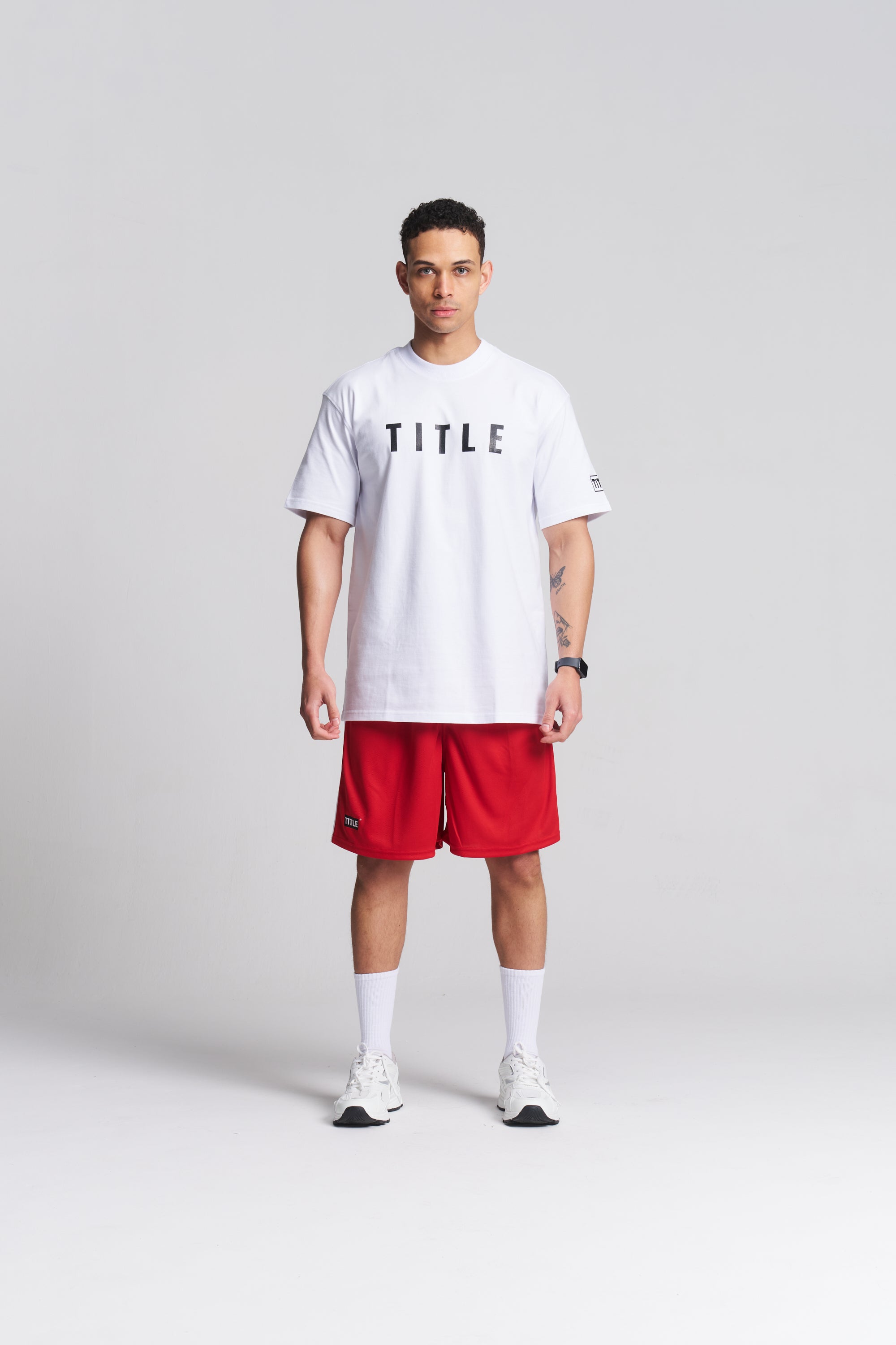 TITLE Boxing South Africa white oversized cotton t-shirt with black chest logo worn by a male model with red shorts