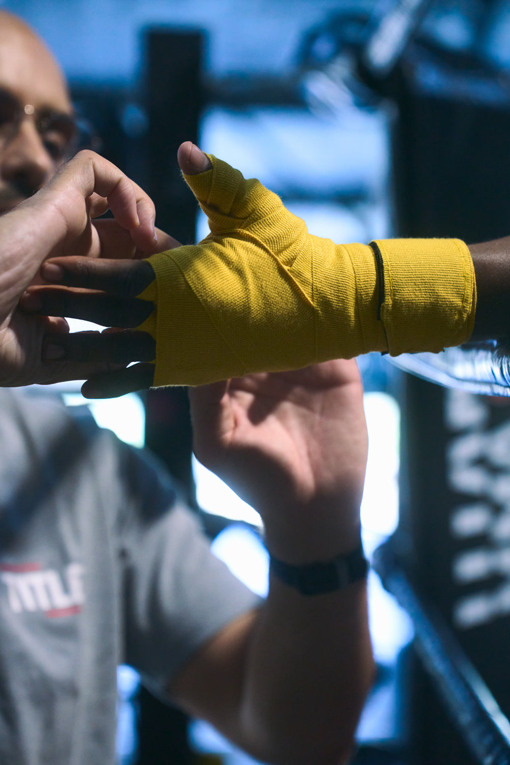 TITLE Boxing South Africa yellow woven cotton hand wraps being applied to a boxer's hand in a gym setting