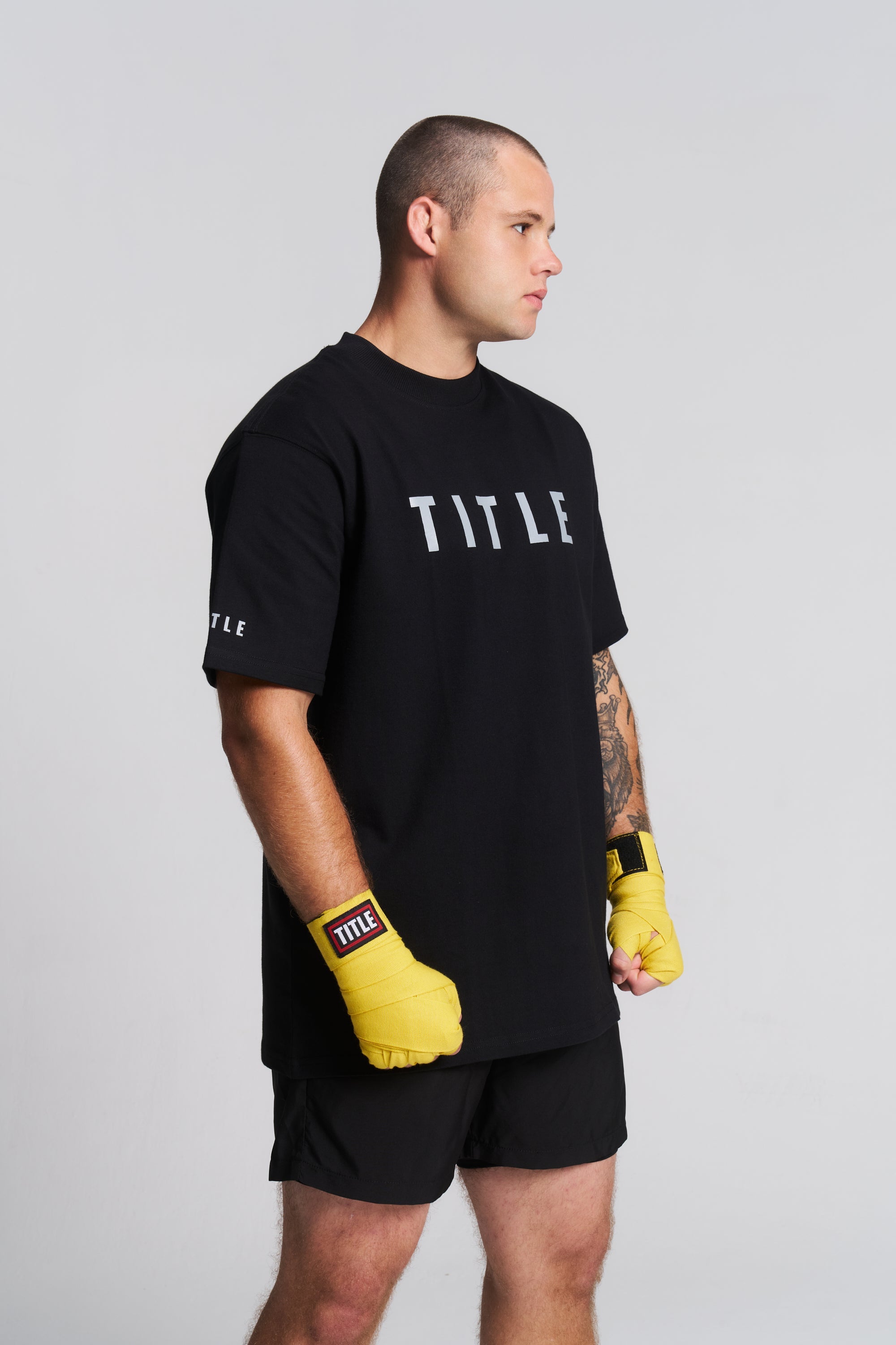 TITLE Boxing South Africa athlete wearing yellow cotton hand wraps and a black branded t-shirt in a studio setting