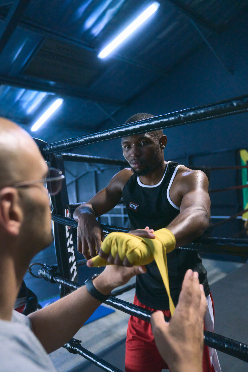 TITLE Boxing South Africa athlete having yellow hand wraps applied by a coach in a boxing ring