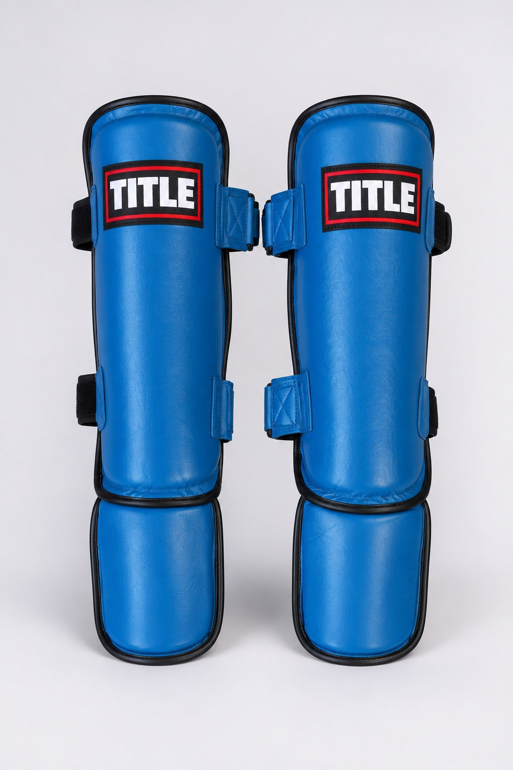 TITLE Contender leather shin guards in blue, front view with red-bordered TITLE patch and padded instep