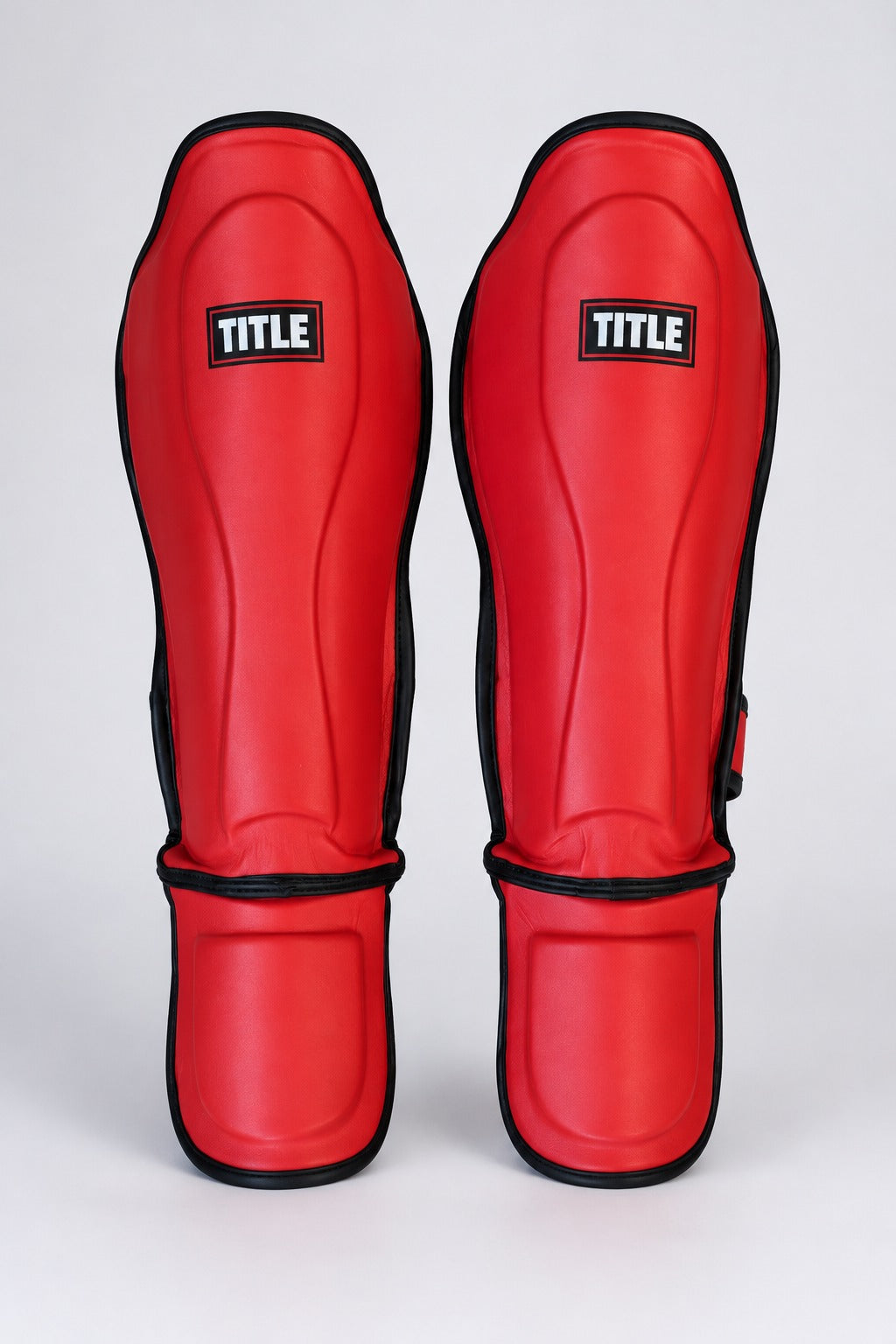 TITLE Fight Camp PU leather shin guards in red, front view showing the contoured shin shell and instep pads