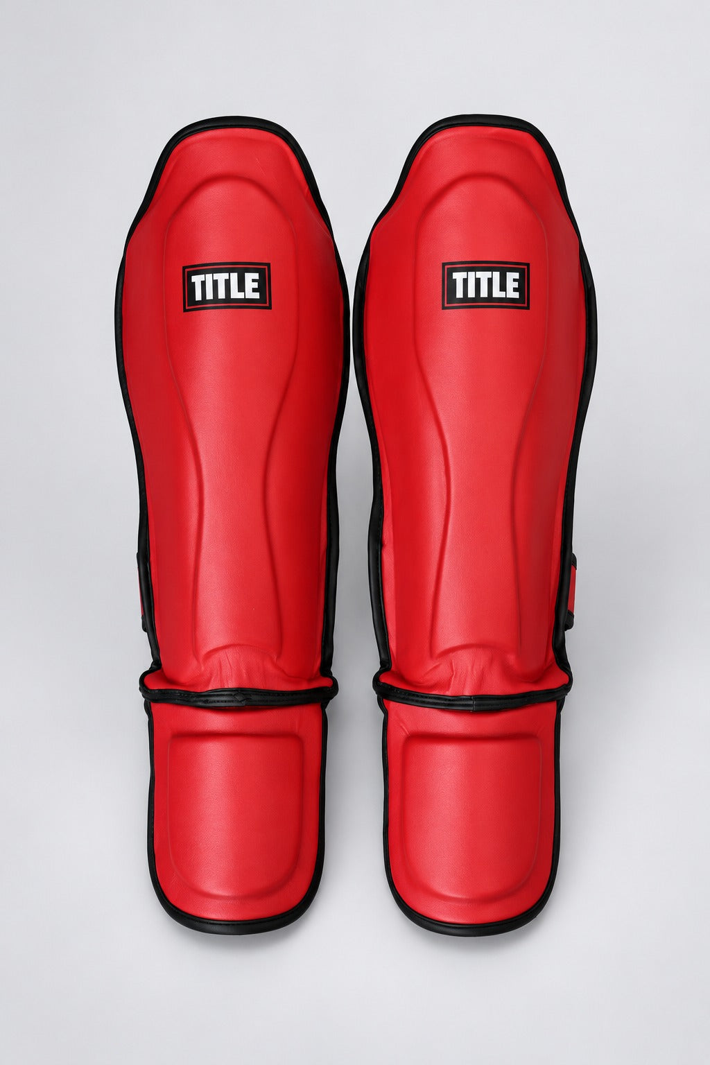 Red PU leather Muay Thai shin guards by TITLE, top-down view of the ribbed shin shell and articulated instep