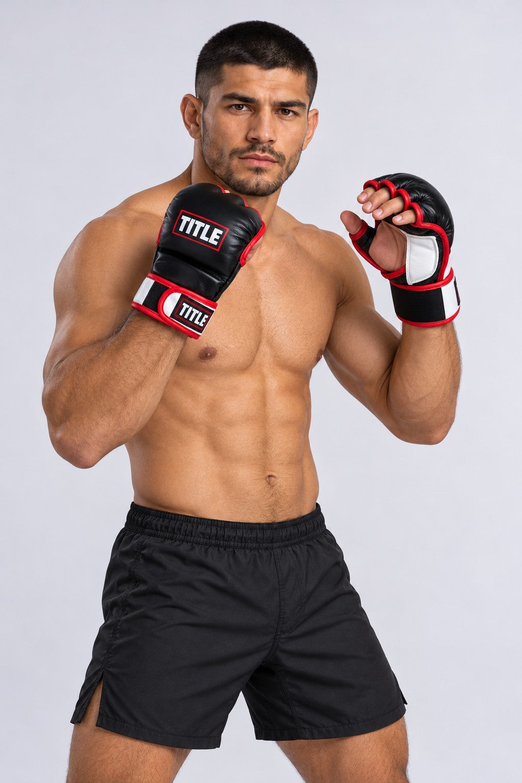 Fighter with one fist up and one hand open, showing the free fingers of TITLE black, red and white leather MMA gloves