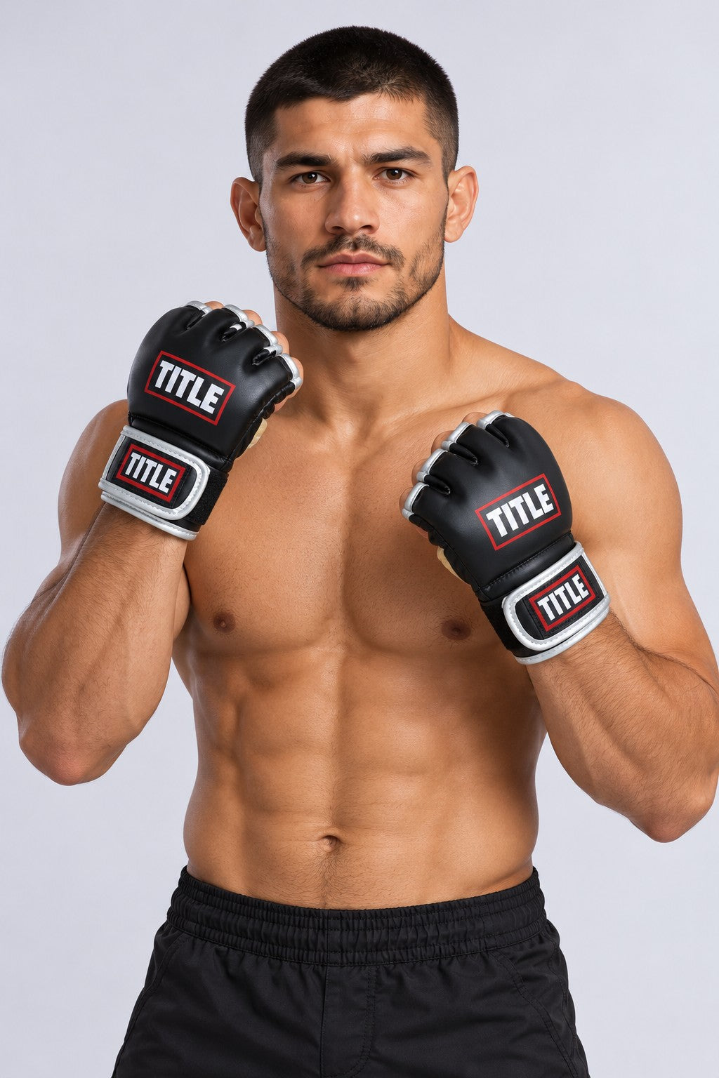 Fighter holding a high guard in TITLE black and silver Powerhide MMA gloves with padded knuckles and finger loops